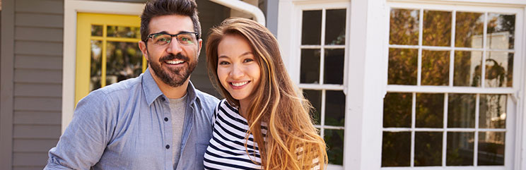 Smiling couple in front of house